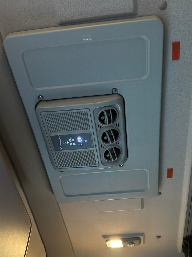 An overhead lorry cab ceiling fixture with a light panel, air conditioning ventilation fans, and a small illuminated display, photographed inside the cabin.