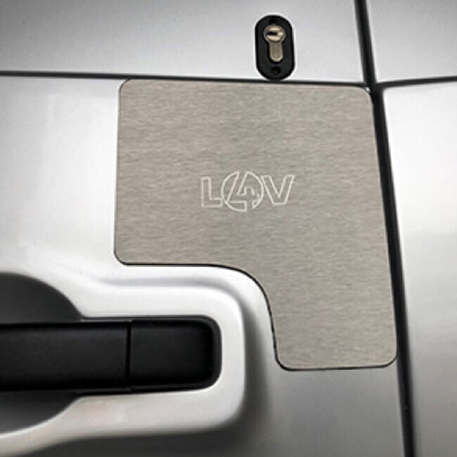 A brushed metal lock shielding kit with an embossed 'L4V' logo, shown installed on the door of a silver van.